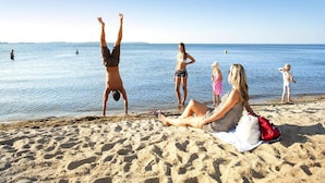 En strandscen med sand, vatten och människor.