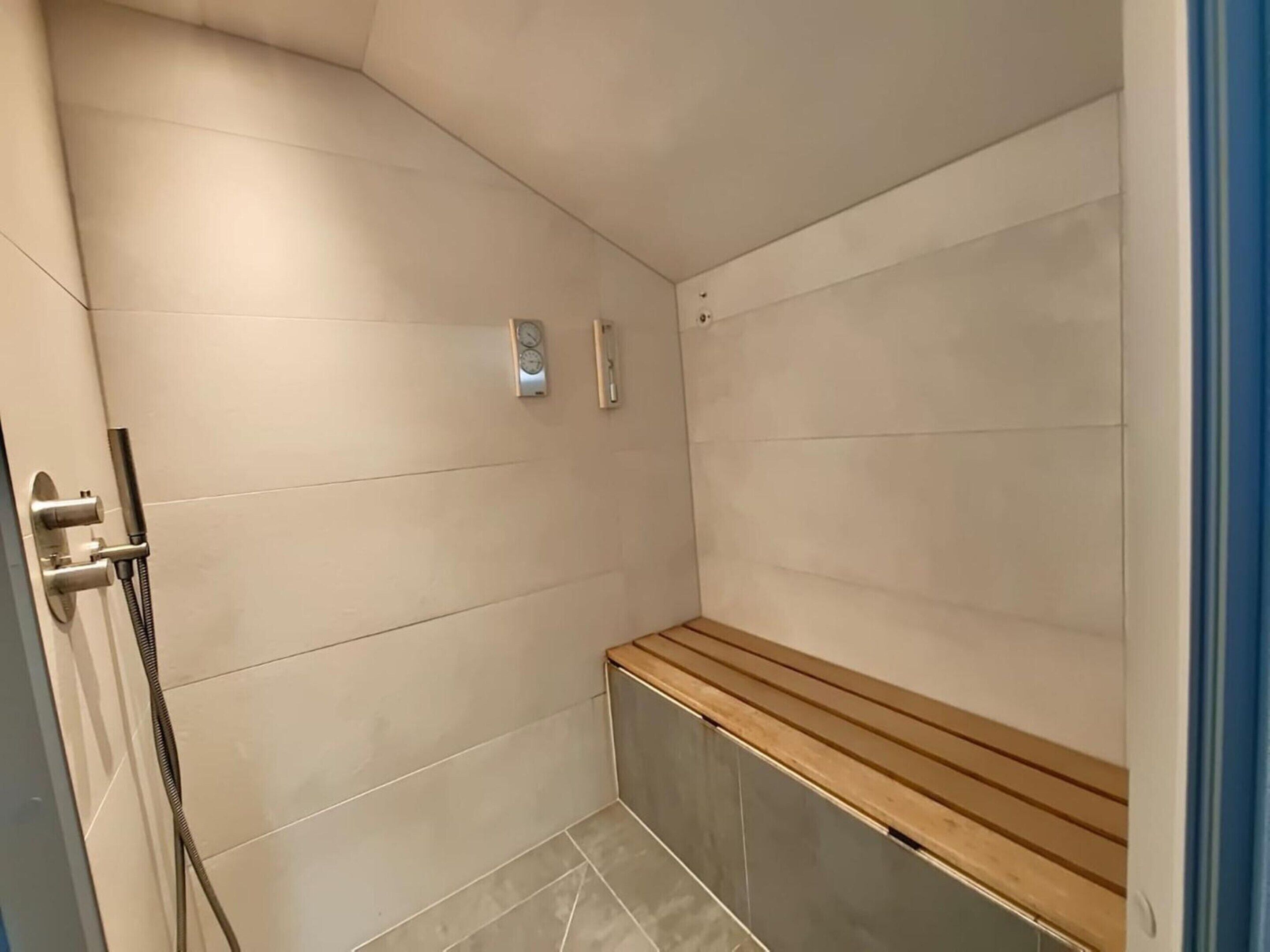 A shower area with a bench, a wall-mounted clock, and a towel rack.