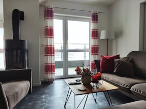A living room with a fireplace, a sofa, a coffee table, and a lamp. - Modernes Apartment mit Blick auf den Hafen in Rechlin (Rechlin)