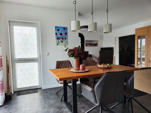 Un comedor moderno con una mesa de madera, sillas negras y un jarrón de flores.