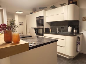 Eine moderne Küche mit weißen Schränken, einer schwarzen Arbeitsplatte und einem eingebauten Backofen.