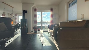 Ett modernt vardagsrum med en öppen spis, en matplats och utsikt genom ett stort fönster.