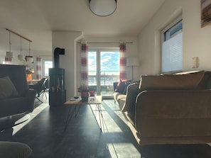 Ein modernes Wohnzimmer mit Kamin, Essbereich und Blick durch ein großes Fenster.