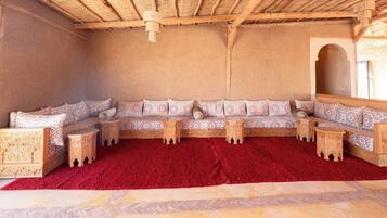 Una habitación con un sofá grande, alfombra roja y techo de paja.