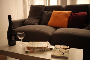 A living room with a sofa, a table with a bottle, a glass, books, and glasses. - Secrets of Vieux Lyon – a unique pedestrian street (Lyon)