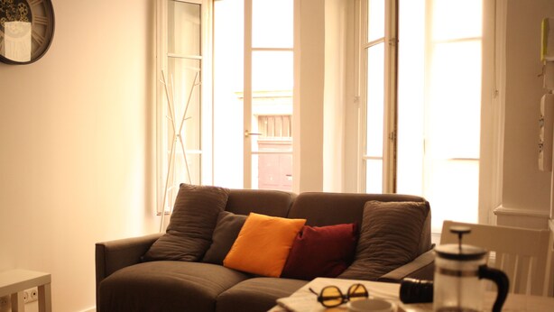 Un salon avec un canapé, une table basse sur laquelle se trouvent une cafetière, des verres et une tasse.