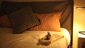 Un lit avec un oreiller, un livre et une lampe de chevet.