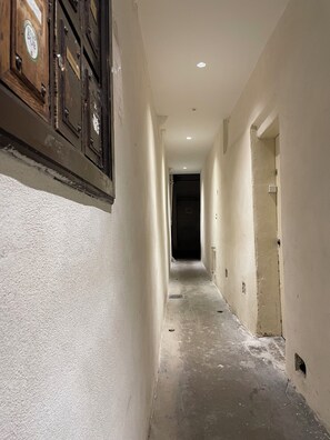 A narrow hallway with white walls, a dark door at the end, and a wooden cabinet on the left. - Secrets of Vieux Lyon – a unique pedestrian street (Lyon)