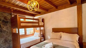 Una habitación de madera con una litera, una pared de piedra y una lámpara colgante.