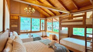 A wooden cabin bedroom with a large bed, two smaller beds, and a chandelier.