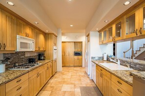 A kitchen with wooden cabinets, a microwave, a stove, and a sink. - Charming 3 bedroom Stone Ridge Townhome (Sunriver)