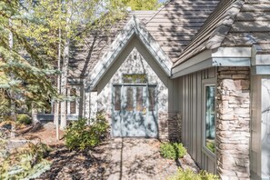 A house with a stone exterior, a gabled roof, and a front door with a window above it. - Charming 3 bedroom Stone Ridge Townhome (Sunriver)