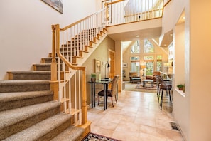 A multi-level home interior with a carpeted staircase, a dining area with a table and chairs, and a living room with a sofa and a coffee table. - Charming 3 bedroom Stone Ridge Townhome (Sunriver)