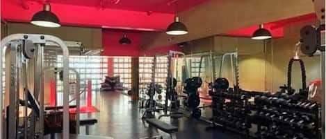 A gym with various exercise equipment, including weight machines, benches, and dumbbells.