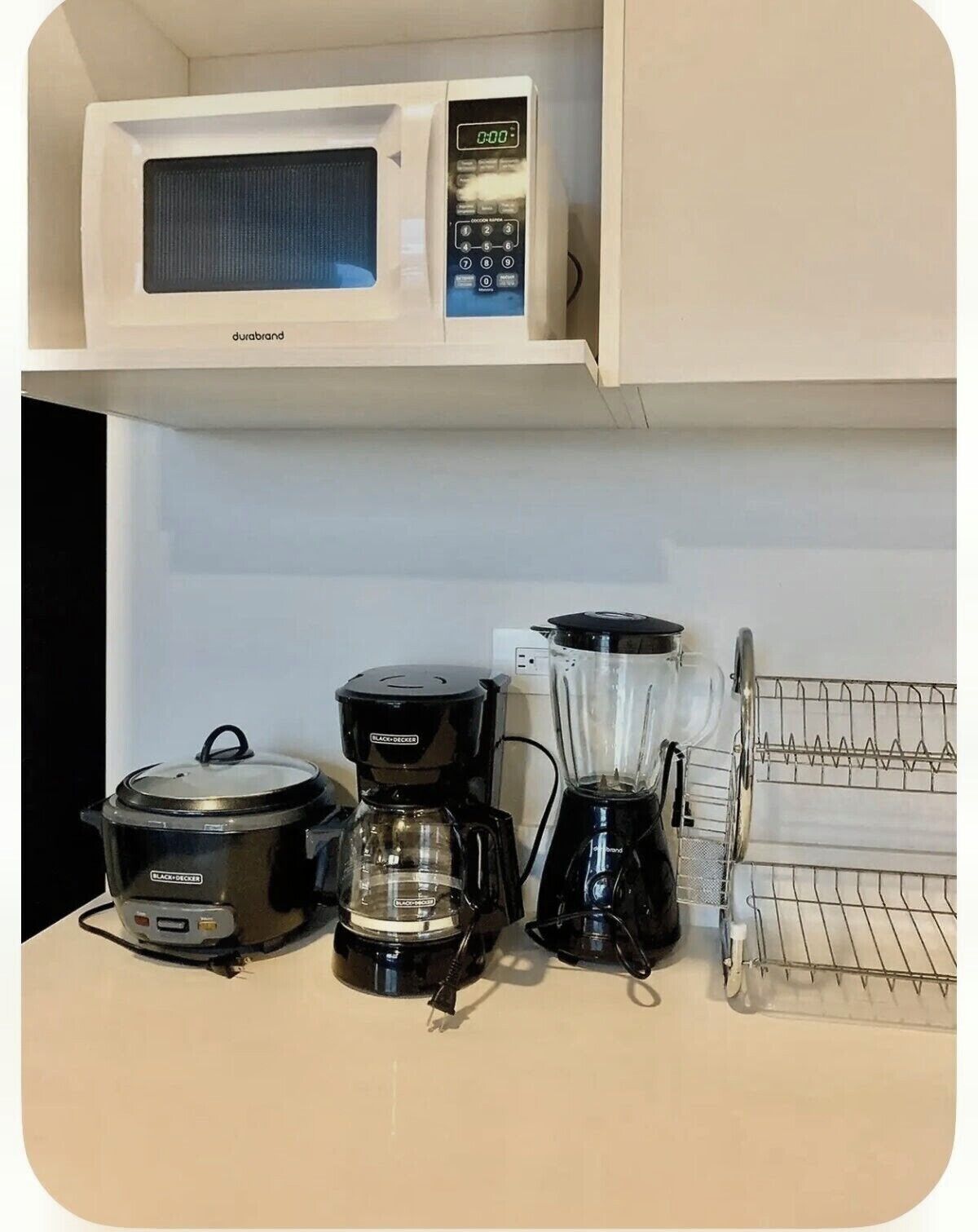 A kitchen with a microwave, a slow cooker, a coffee maker, and a blender on the counter.