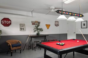 A pool table with a red felt surface, a stop sign, and various road signs on the wall. - 6Bedroom Luxury Pool Villa near Disney & Free Resort (Four Corners)