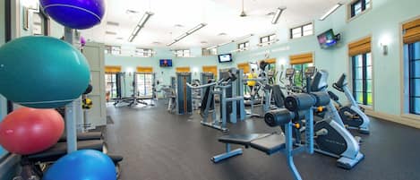 A gym with exercise equipment, a television, and a wall-mounted screen.