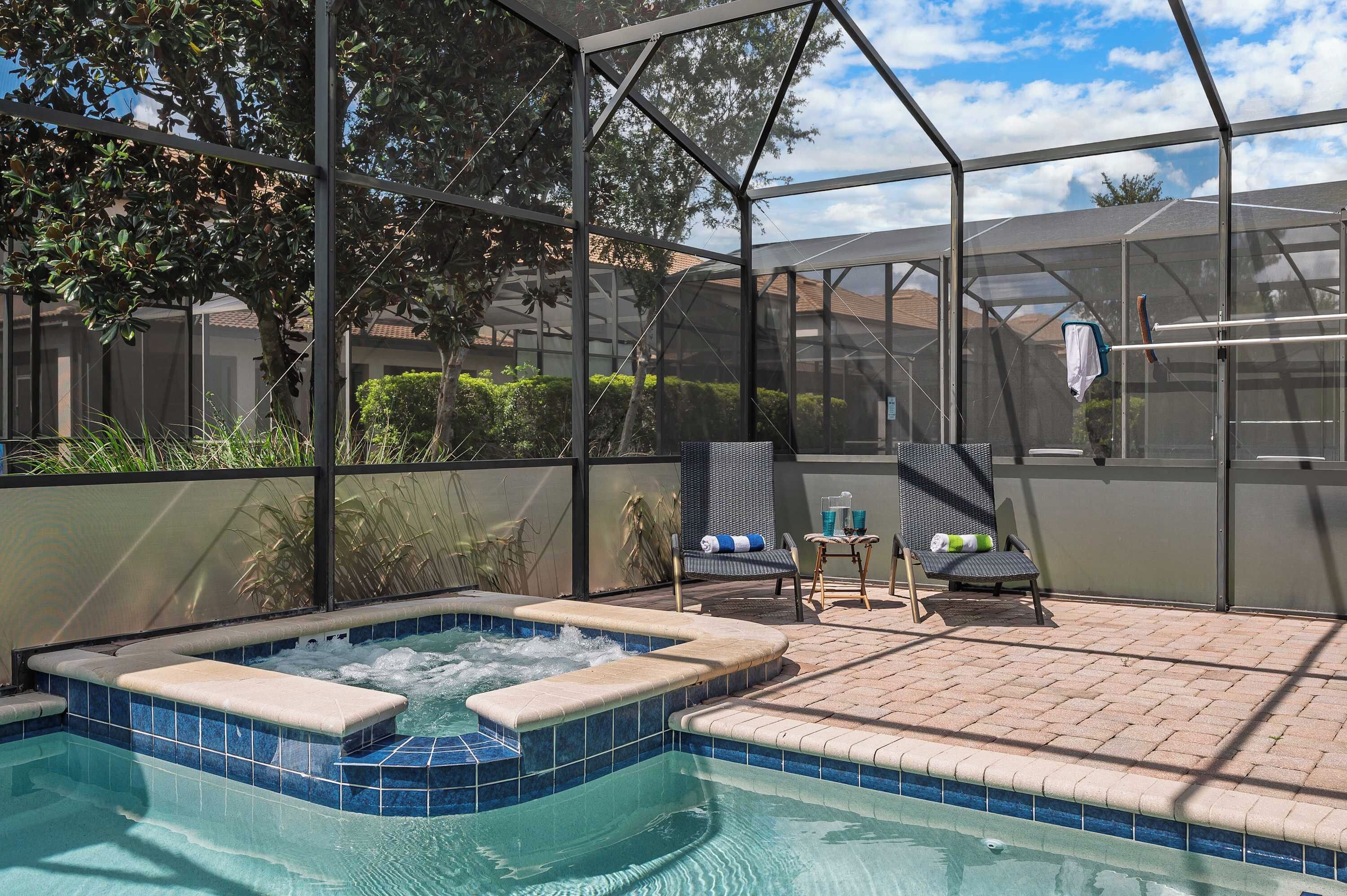 Ein vom Glas umschlossener Poolbereich mit Whirlpool, Liegestühlen und einer Terrasse.