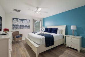 Ein Schlafzimmer mit einem Bett, einem Nachttisch, einer Kommode und einem Deckenventilator.