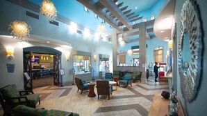 Een ruime lobby met hoge plafonds, moderne verlichtingsarmaturen en comfortabele zithoeken.