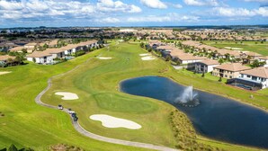 Een golfbaan met bunkers, een vijver en een fontein.