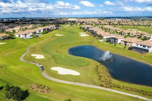 Ein Golfplatz mit Bunkern, einem Teich und einer Springfontäne.