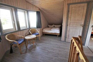 Ein kleiner, gemütlicher Raum mit schrägen Wänden, einem Bett, zwei Korbstühlen, einem kleinen runden Tisch und einer Tür.