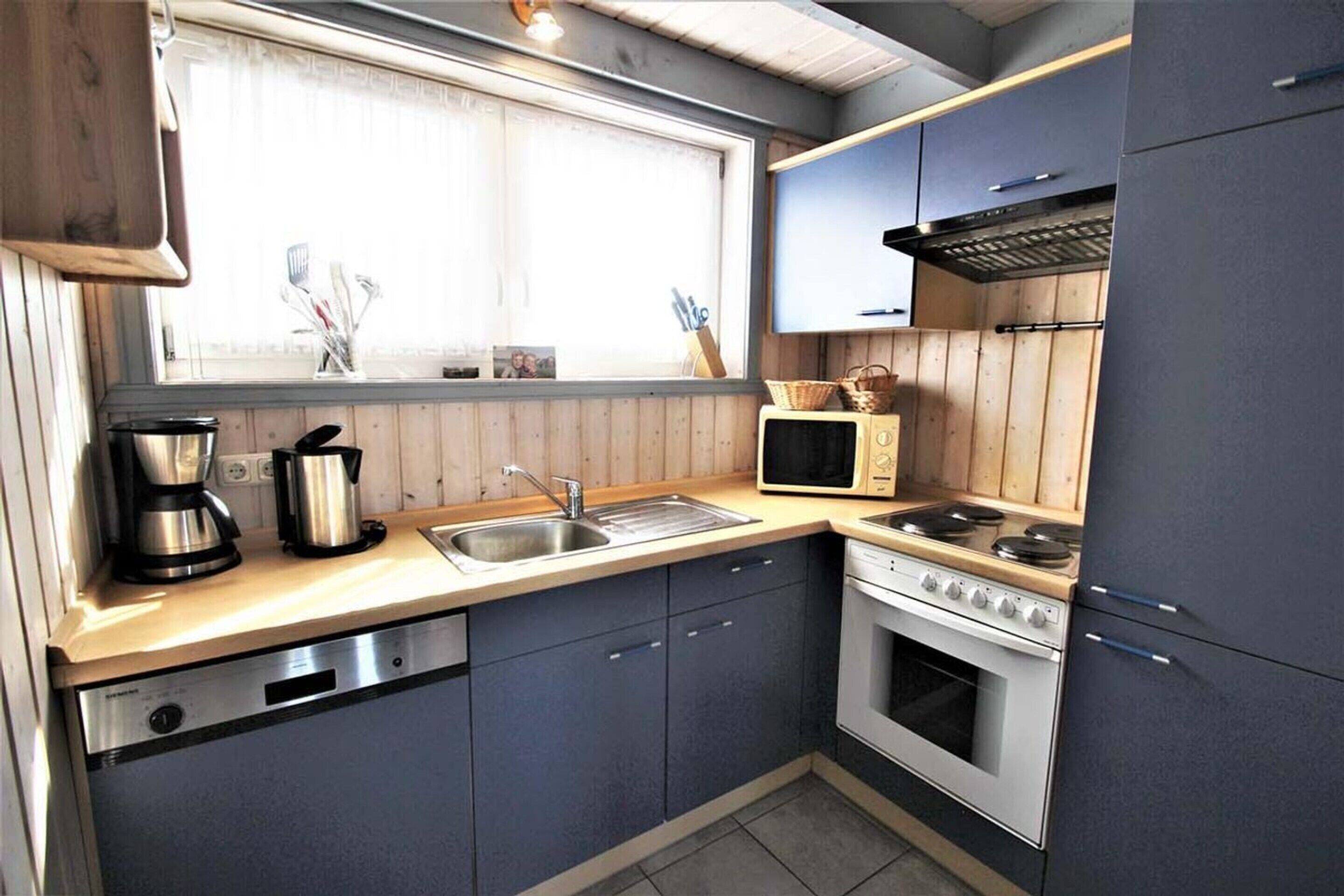 A compact kitchen with a sink, stove, and microwave.