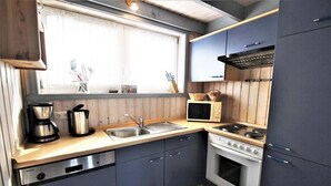 A compact kitchen with a sink, stove, and microwave. - Ferienhaus im Skandinavischen Stil mit Garten im Hafendorf Rechlin (Rechlin)