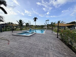 A swimming pool with a tiled deck, surrounded by palm trees and a clear sky. - Fairway Retreat with beach access in Drax Hall (Saint Ann's Bay)