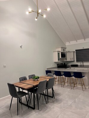 A modern kitchen with white cabinets, a black microwave, and a bar area with blue chairs. - Fairway Retreat with beach access in Drax Hall (Saint Ann's Bay)
