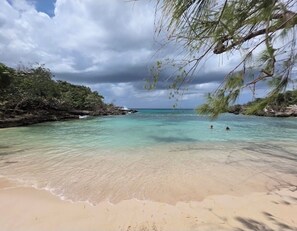 A beach with clear turquoise water, sandy shore, and lush greenery. - Fairway Retreat with beach access in Drax Hall (Saint Ann's Bay)