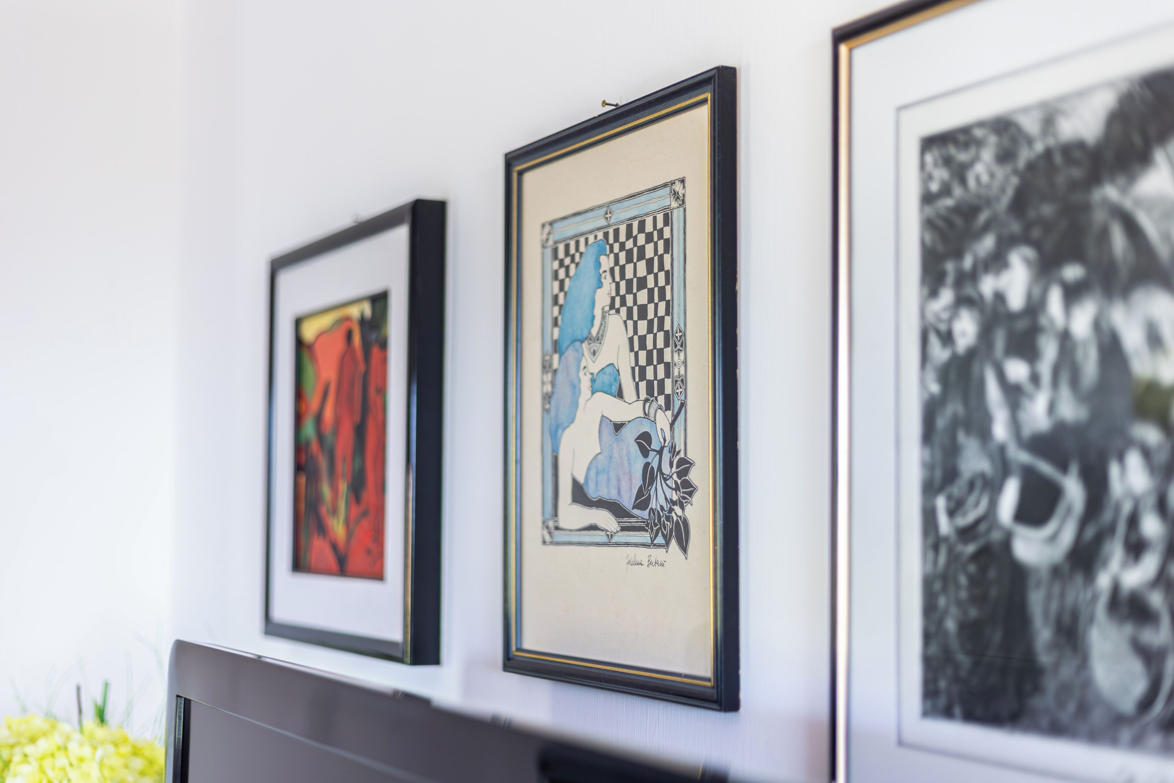 Eine Wand mit drei gerahmten Kunstwerken.