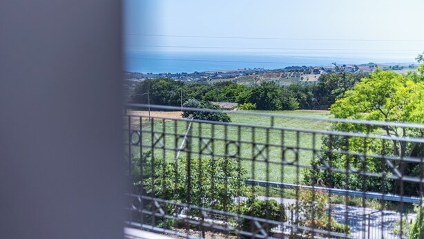 A view from a balcony with a metal railing, overlooking a green landscape with trees and a distant view of the sea. - Villino Boschetti—A terrace just 15 minutes from the beach in Vasto (Abruzzo)