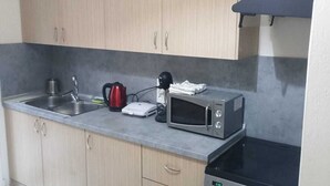 A compact kitchen with a microwave, kettle, and a small oven.