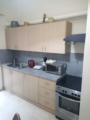 A compact kitchen with a microwave, kettle, and a small oven.