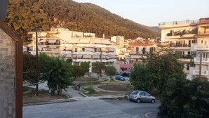 A residential area with multiple two-story buildings, a parking lot with cars, and a hilly backdrop.
