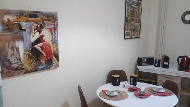 A dining area with a round table, chairs, and a painting on the wall.