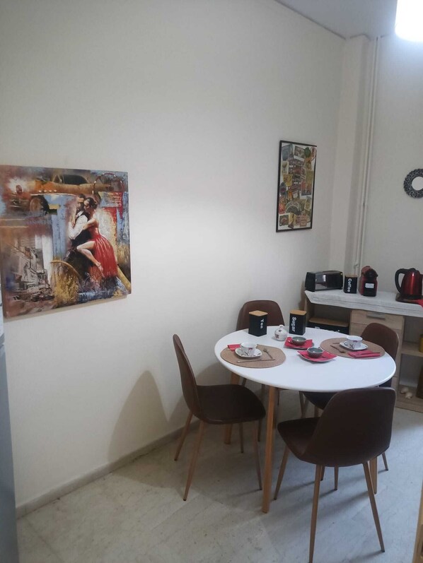A dining area with a round table, chairs, and a painting on the wall.