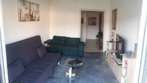A compact living space with a sofa, a coffee table, and a kitchenette area.