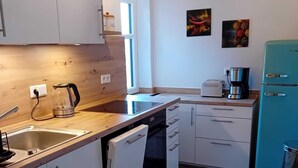 A modern kitchen with white cabinets, a dishwasher, a coffee maker, and a teal refrigerator. - Charming vacation rental with garden access, about 4 km from the North Sea (Dagebüll) (Galmsbüll)
