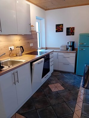 A modern kitchen with white cabinets, a dishwasher, a coffee maker, and a teal refrigerator. - Charming vacation rental with garden access, about 4 km from the North Sea (Dagebüll) (Galmsbüll)