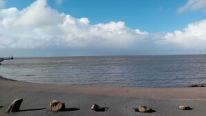 A beach with a clear sky, calm sea, and wind turbines in the distance. - Charming vacation rental with garden access, about 4 km from the North Sea (Dagebüll) (Galmsbüll)