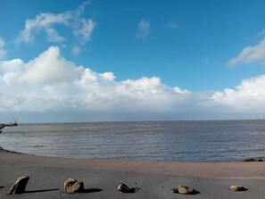 A beach with a clear sky, calm sea, and wind turbines in the distance. - Charming vacation rental with garden access, about 4 km from the North Sea (Dagebüll) (Galmsbüll)