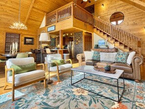 Un vaste espace de vie doté d’un haut plafond, d’un escalier en bois et d’un coin repas aménagé avec des meubles modernes.