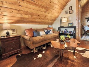 Ein gemütliches Wohnzimmer mit Holzboden, einem braunen Ledersofa, einem Couchtisch aus Holz mit Pflanzen und einem Cowhide-Teppich.
