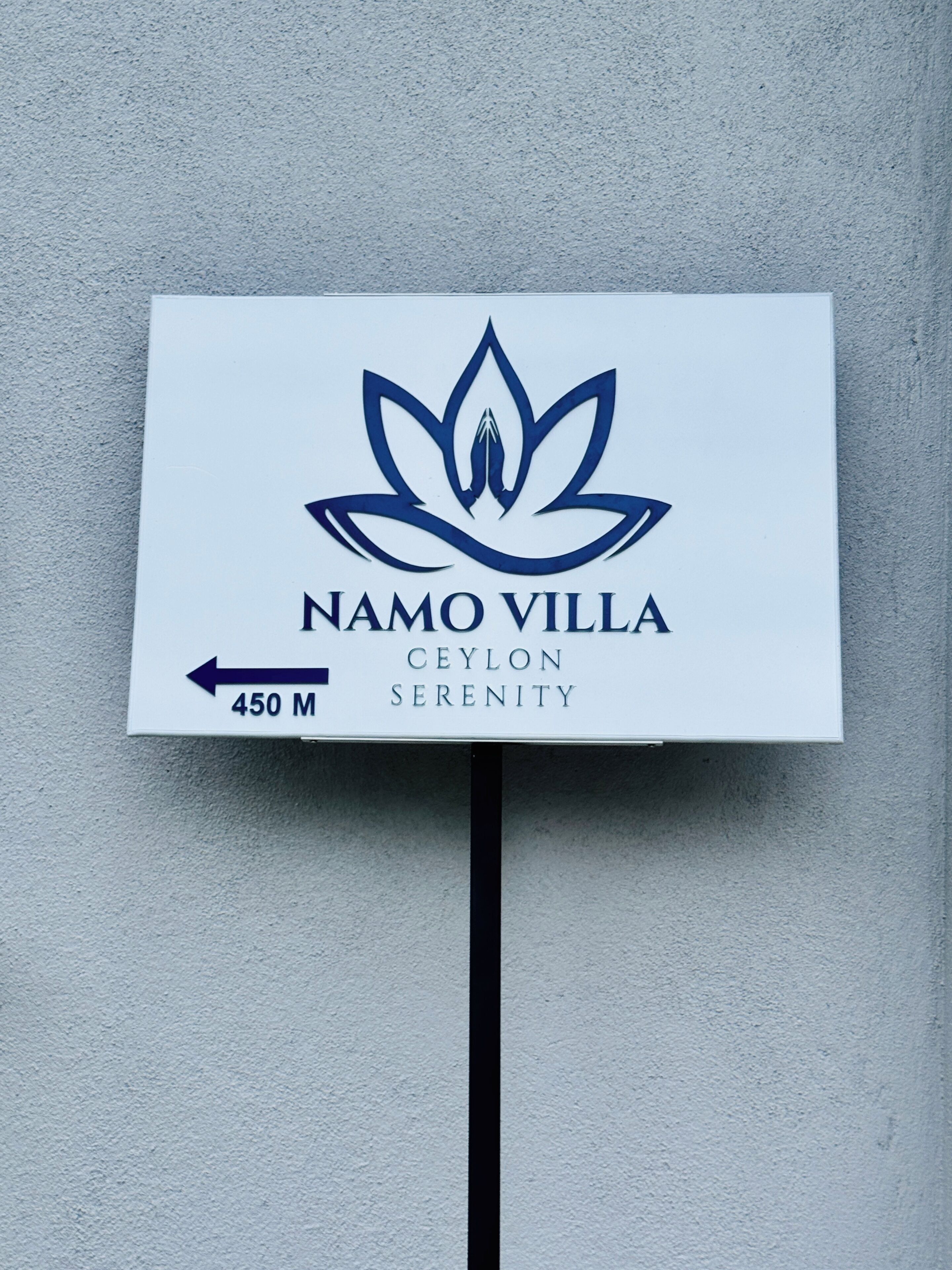 A sign for Namo Villa with a lotus symbol, indicating a serene location.