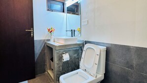 A bathroom with a toilet, sink, mirror, and a door. - Namo Villa Habaraduwa (Habaraduwa)