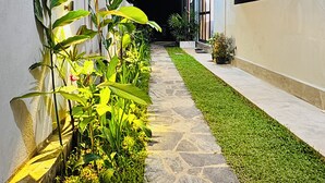 A pathway leading to a building with a stone border and a well-maintained lawn. - Namo Villa Habaraduwa (Habaraduwa)