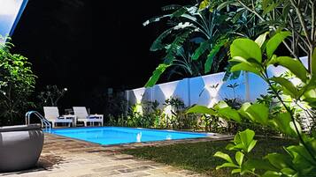 Zona de piscina con sillones de descanso y patio de piedra.